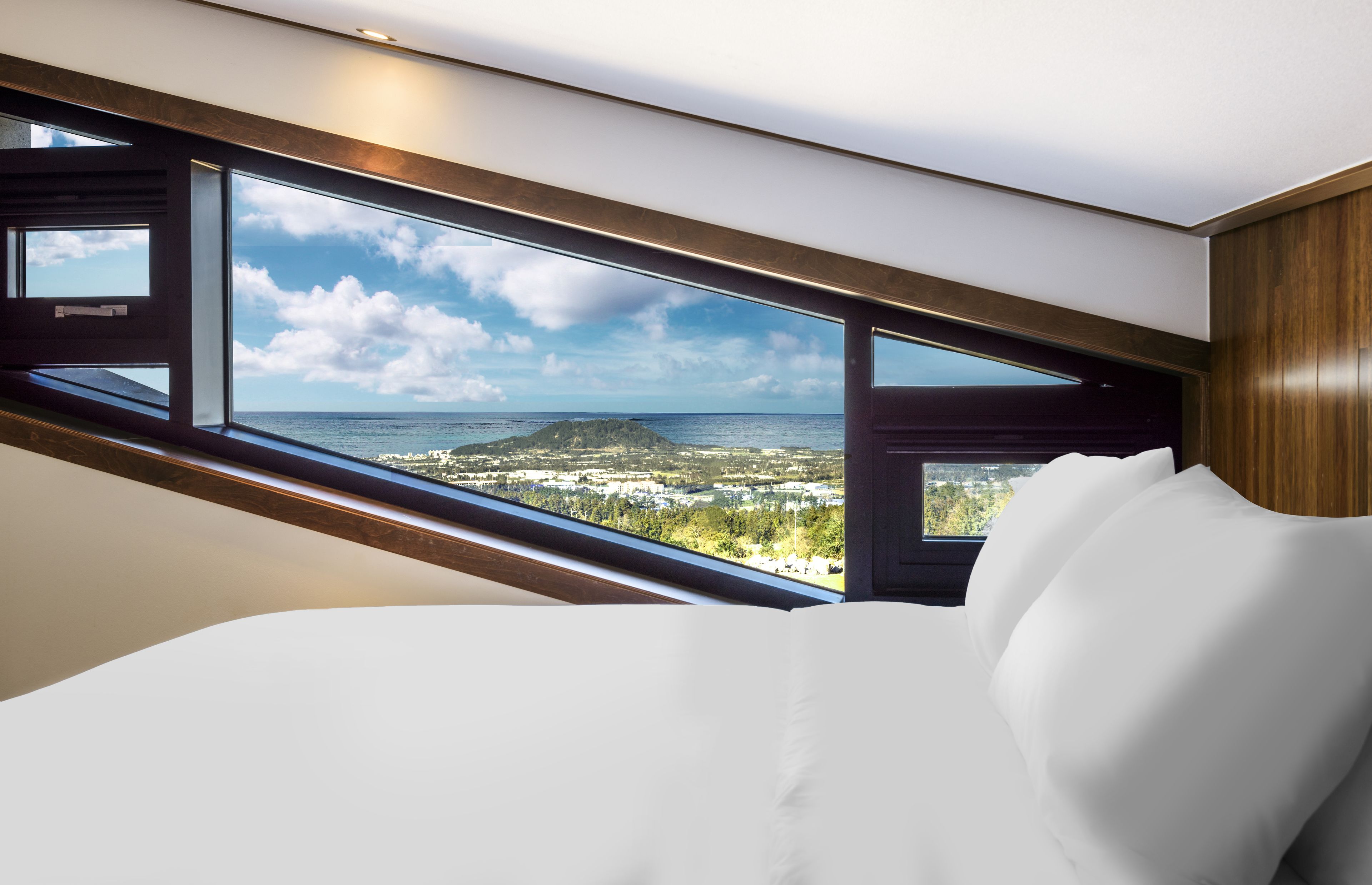 Un dormitorio con un ventanal grande que ofrece vistas a un paisaje costero.