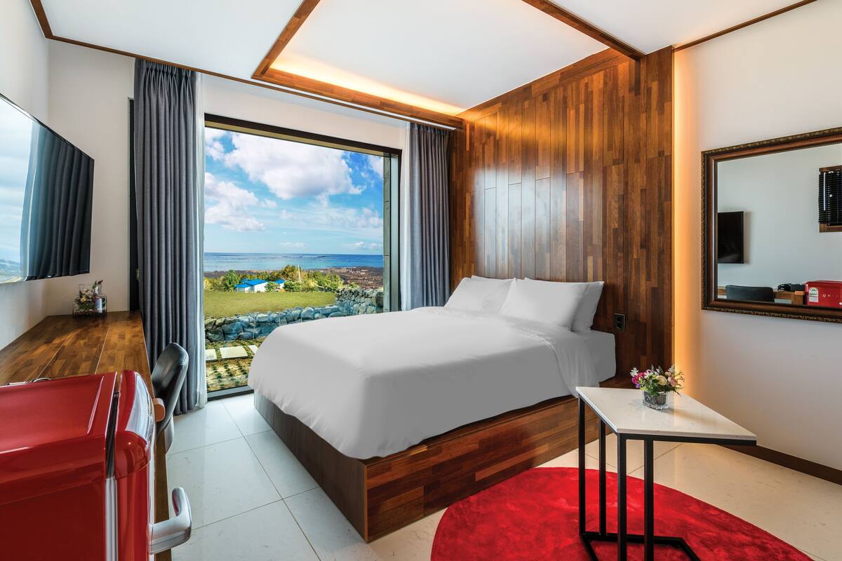 Ein modernes Hotelzimmer mit einem großen Bett, einem Schreibtisch und Blick auf den Ozean.