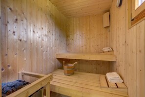 Un sauna en bois avec des bancs, un seau et des serviettes.