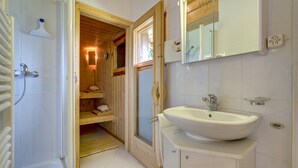 Une salle de bain avec une douche en bois, un lavabo blanc et un miroir au-dessus.