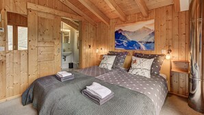Une chambre à coucher dans une cabane en bois, avec un lit, deux tables de chevet, un tableau et une fenêtre.
