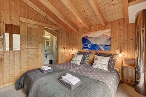 Une chambre à coucher dans une cabane en bois, avec un lit, deux tables de chevet, un tableau et une fenêtre.