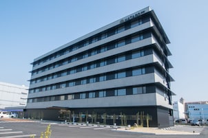 Un hotel de varios pisos con diseño moderno, que presenta un techo plano y una serie de ventanas en cada planta.