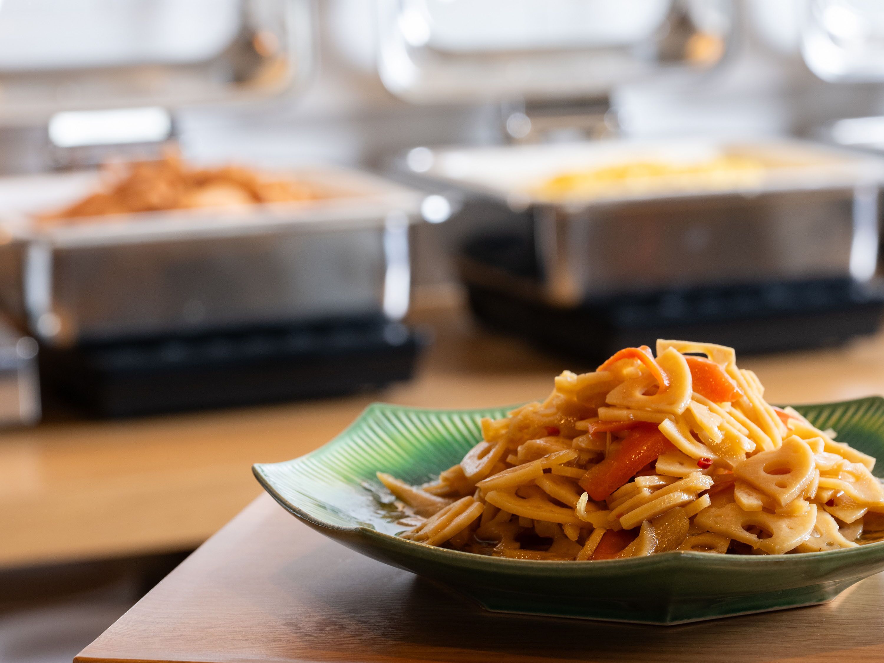 Ein Teller mit grüner Soße, Pasta und Gemüse im Detail.