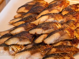 Primer plano de pescado a la parrilla dispuesto en un plato.