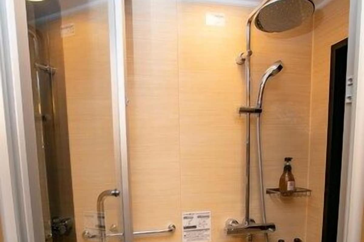Une douche équipée d’un pommeau de douche à main, d’un robinet mural et d’un pommeau de douche à main.