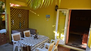 A patio with a table and chairs, a bench, and a door leading to an interior space. - Apartment in residence (Blue Bay)