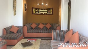 A living room with striped sofas, a coffee table, and decorative wall art. - Apartment in residence (Blue Bay)