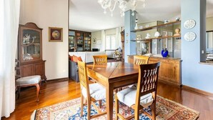 Un comedor con mesa y sillas de madera, una lámpara de araña y un tapete estampado.