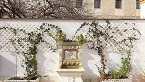 A white lattice wall with climbing plants and a decorative stone structure in the center. - Arrayán. 3 bedrooms  in Macarena (Sevilla)