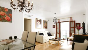 Amplio salón con mesa de comedor de cristal, sofá blanco y una araña.