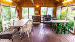 Um deck coberto com churrasqueira, mesa e cadeiras.