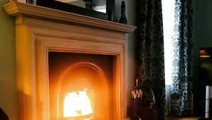 Ein Kamin mit Feuer, eine Couch und eine dekorative Vase.