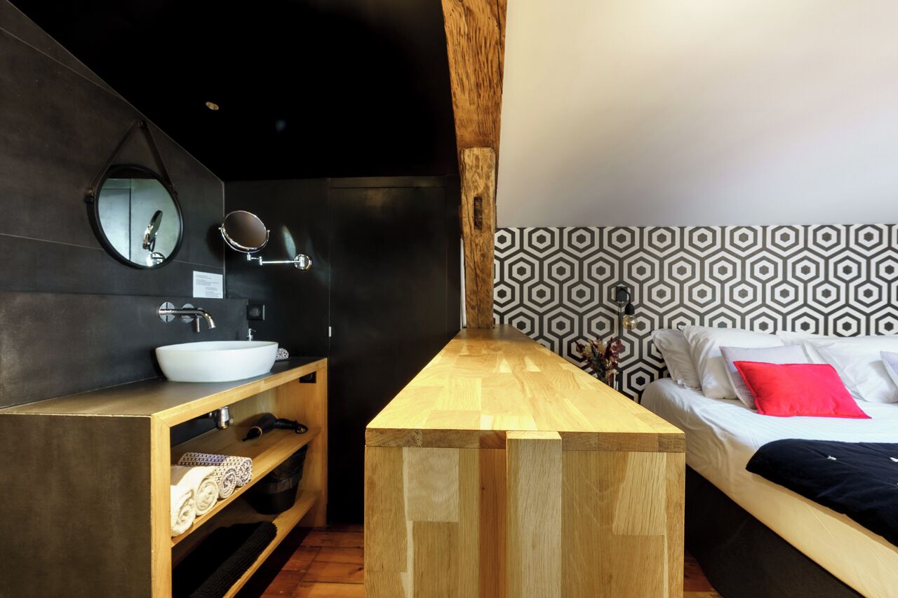 A modern bathroom with a wooden vanity, a round mirror, and a white sink.