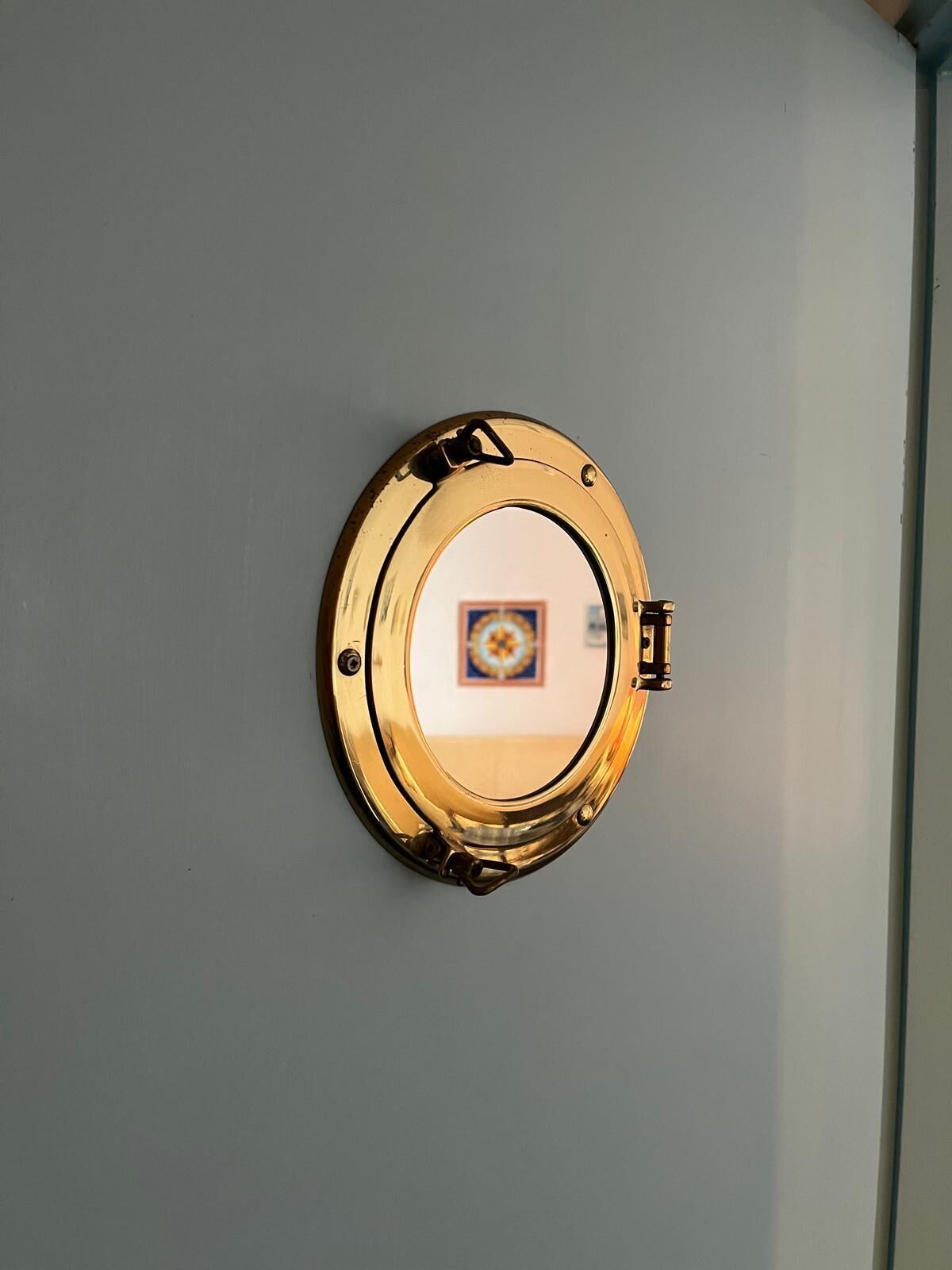 A circular, gold-colored object mounted on a light gray wall.