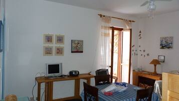 A room with a desk, computer, chair, bed, and a ceiling fan.