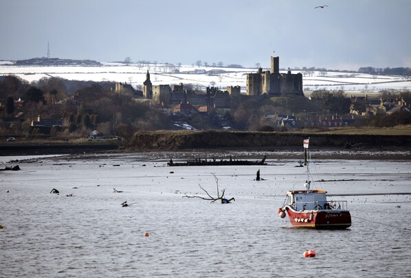 A castle on a hill with a river in the foreground. - CROSS HOUSE APARTMENT Dog Friendly Barn Conversion in the Heart of Warkworth (Warkworth)
