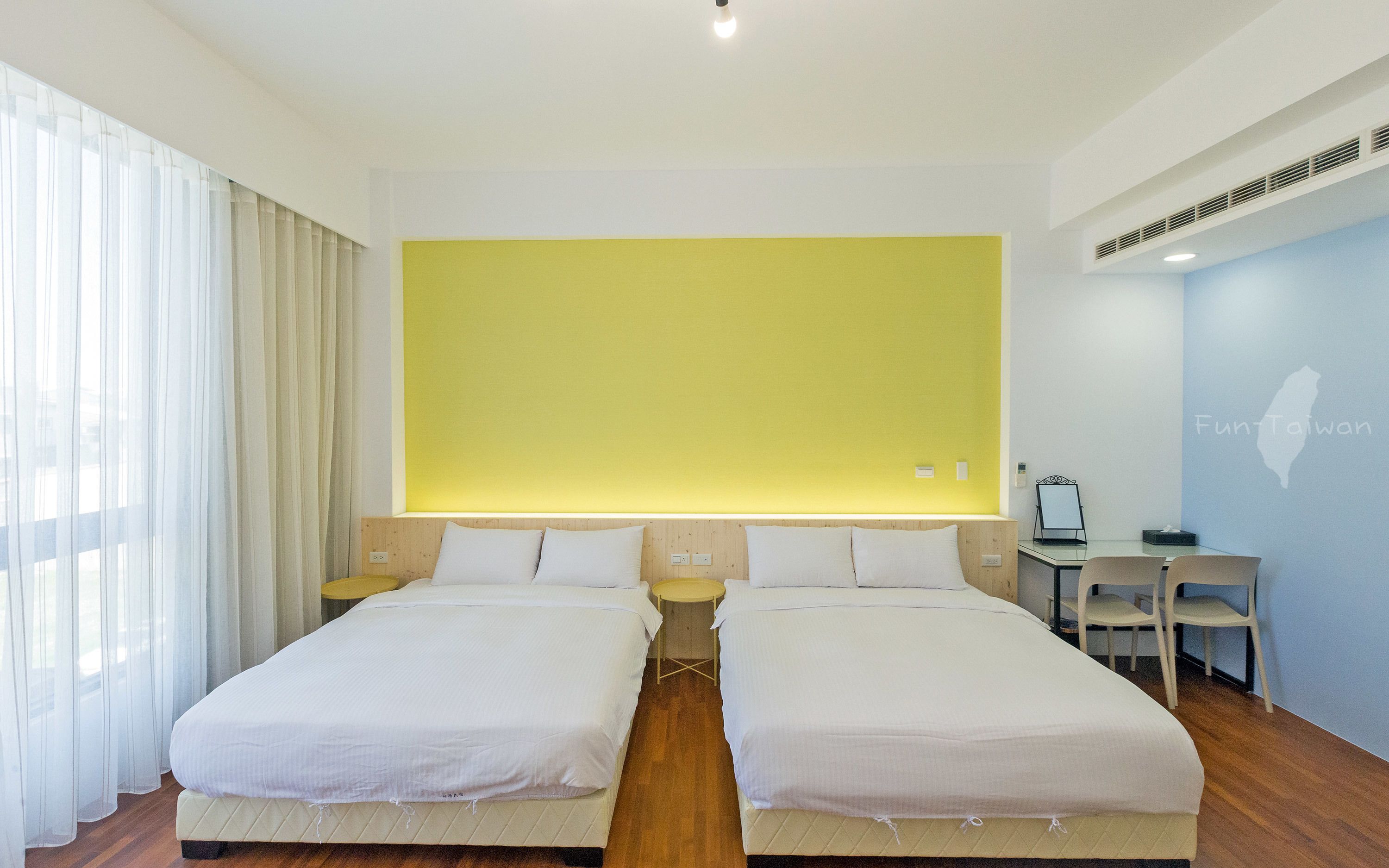A hotel room with two beds, a desk, and a chair.