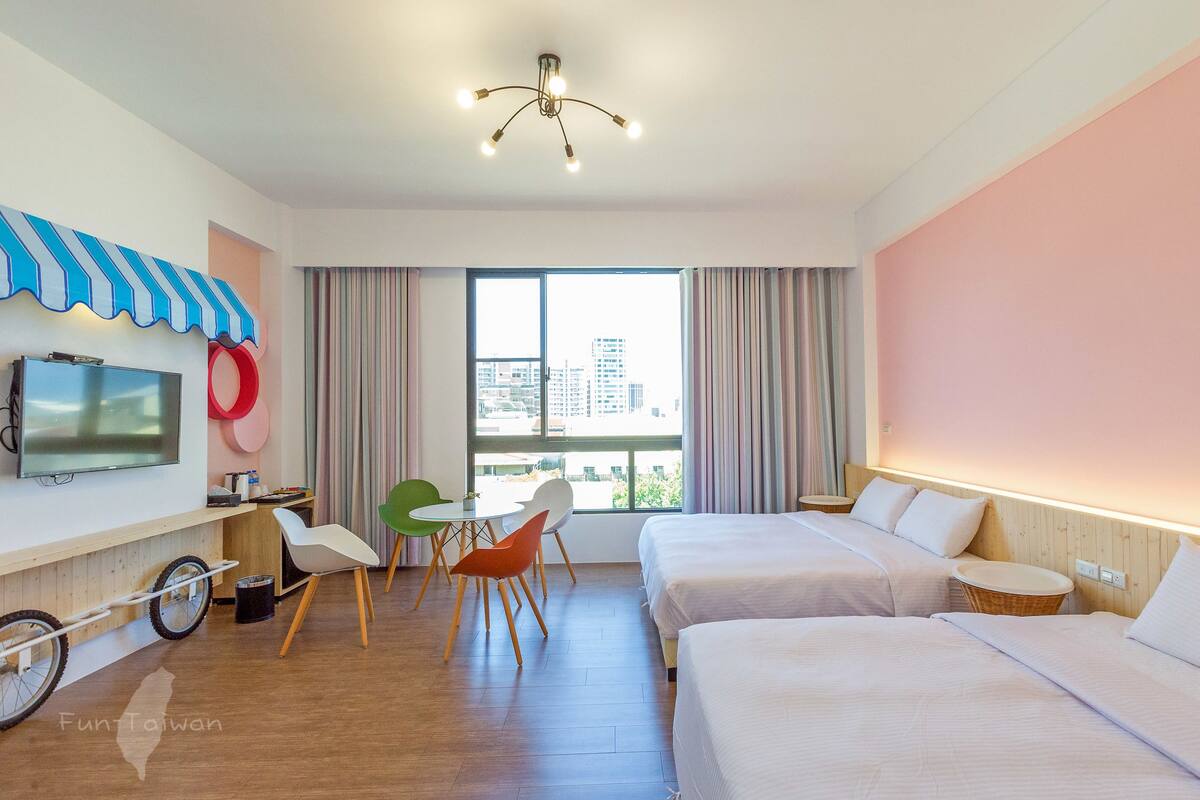 Habitación de hotel con dos camas, televisión, bicicleta y vista a la ciudad.