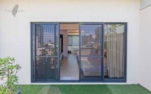 Un bâtiment moderne doté de grandes portes coulissantes en verre qui donnent sur un balcon offrant une vue sur la ville.