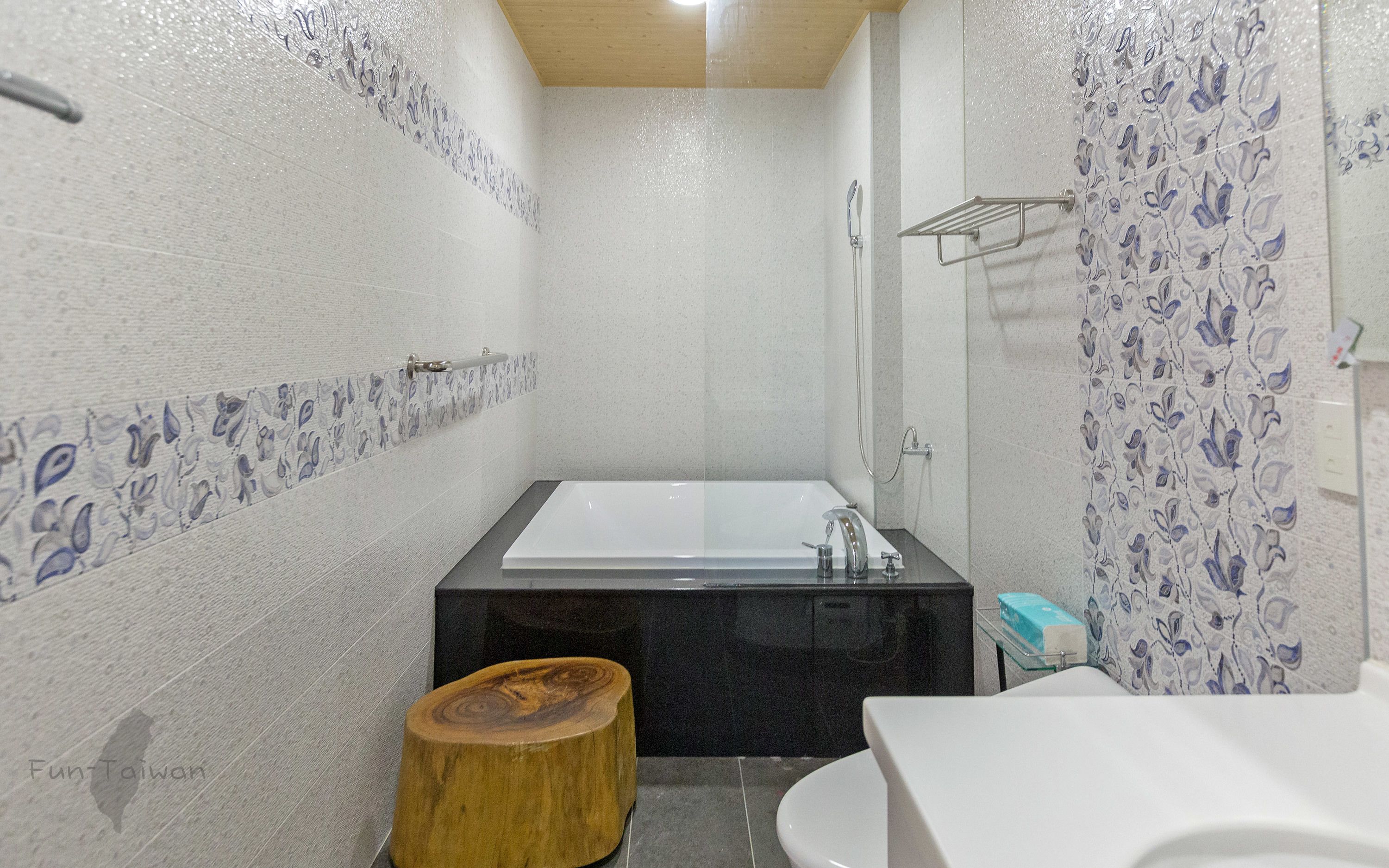 A modern bathroom with a bathtub, a wooden stool, and a toilet.