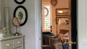 A room with a white dresser, a blue sofa, and a door leading to another room. - Riverside cottage in a beautiful garden in Lincolnshire. (Boston)