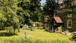 A garden with a gazebo, a brick house, and a lawn. - Riverside cottage in a beautiful garden in Lincolnshire. (Boston)