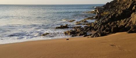 A beach with a rocky shoreline and a clear view of the ocean.