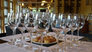 A table with multiple wine glasses and a plate of pastries in a restaurant setting. - GRANMONTE Wine Cottage (Pak Chong)