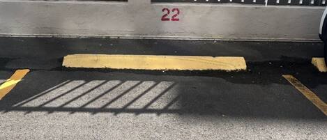 A parking area with a white metal fence, a yellow line, and the number 22 painted on the wall.