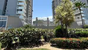 Ein moderner Wohnkomplex mit mehreren Etagen, Balkonen und einem gepflegten Garten mit verschiedenen Pflanzen und Blumen.