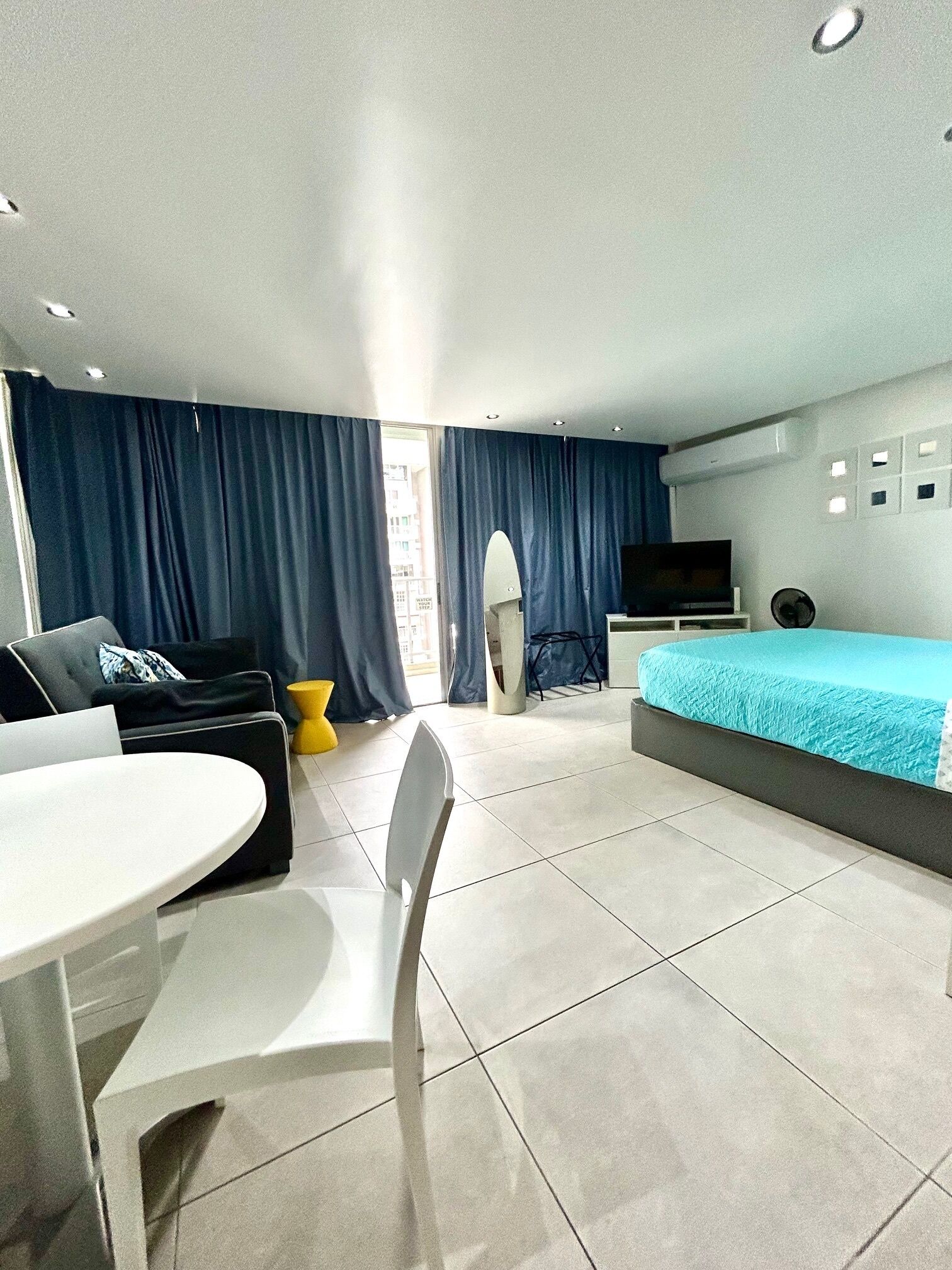Ett modernt hotellrum med en säng, en TV, ett matbord och en soffa.