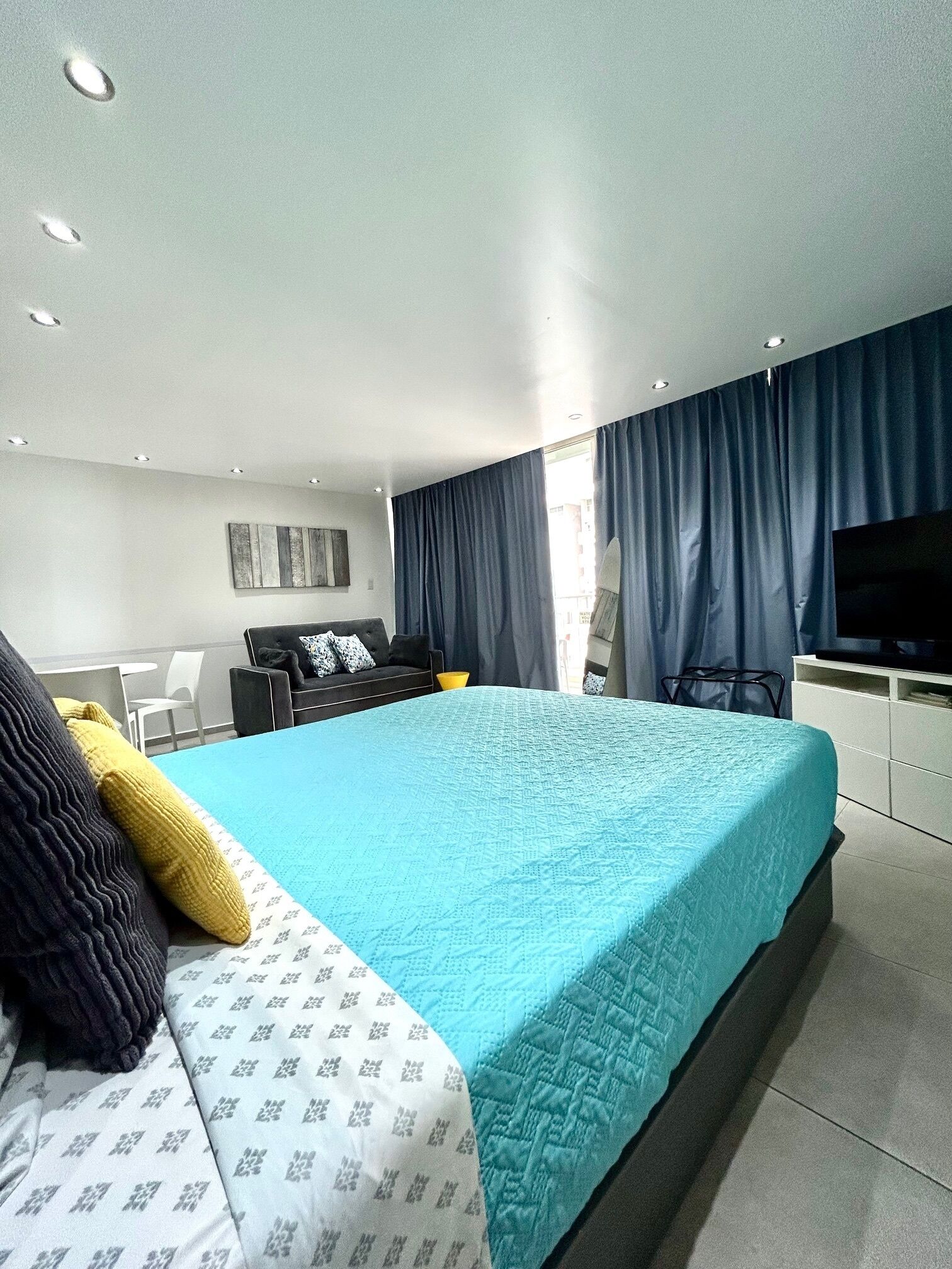Quarto moderno com uma cama grande, uma TV e uma escrivaninha.