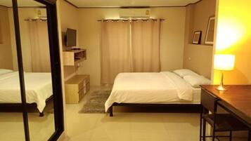A hotel room with two beds, a desk, a TV, and a lamp.