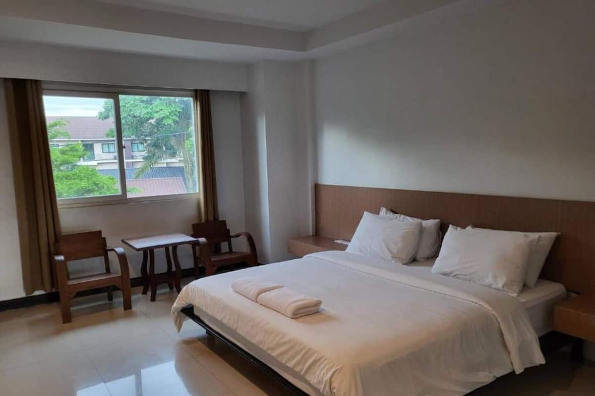 Quarto de hotel com cama, escrivaninha e cadeira.