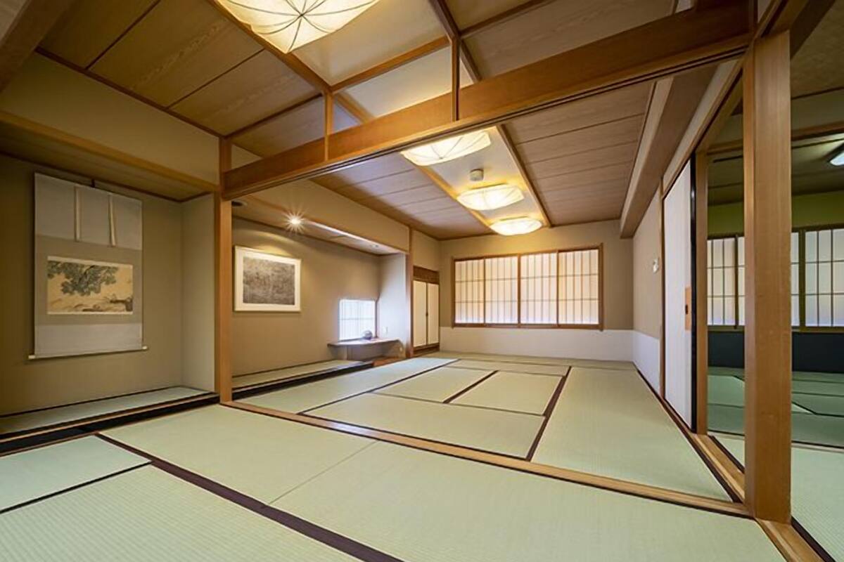 A tatami mat room with sliding doors, a ceiling fan, and artwork on the walls.
