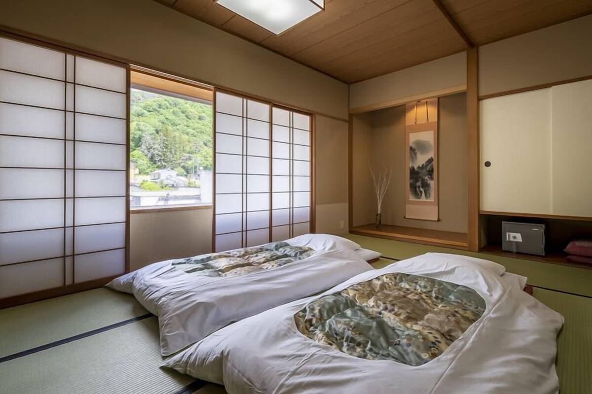 A traditional Japanese room with tatami flooring, shoji screens, and a futon bed.
