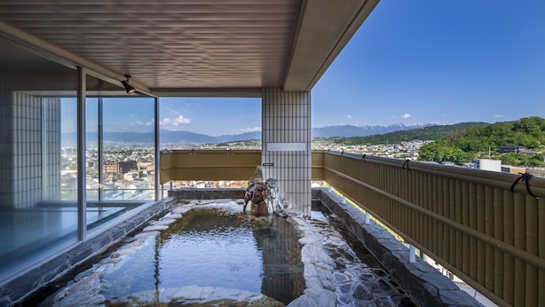 Zona de aguas termales con vistas a un paisaje urbano y montañas.