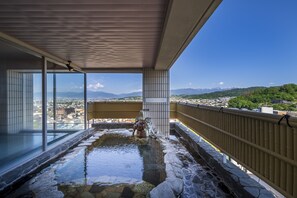 Zona de aguas termales con vistas a un paisaje urbano y montañas.