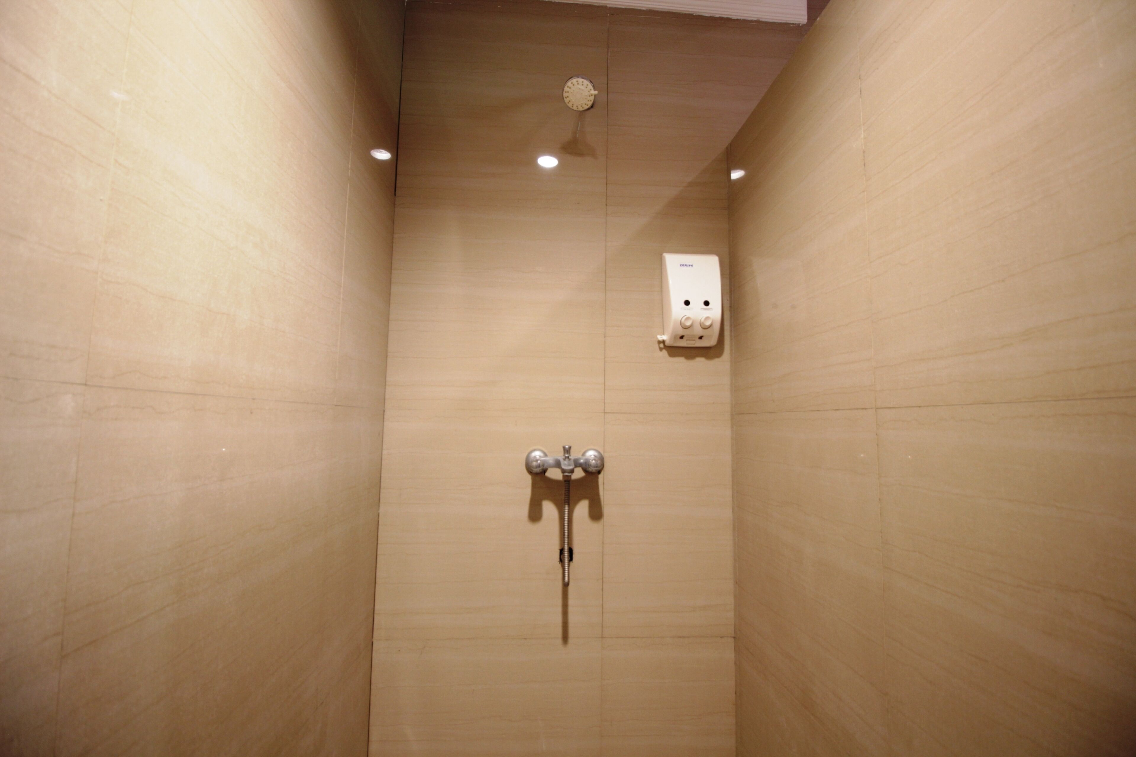 Una ducha con panel de control en la pared y cabezal de ducha de mano.