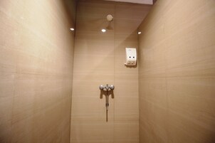 A shower with a wall-mounted control panel and a handheld showerhead.
