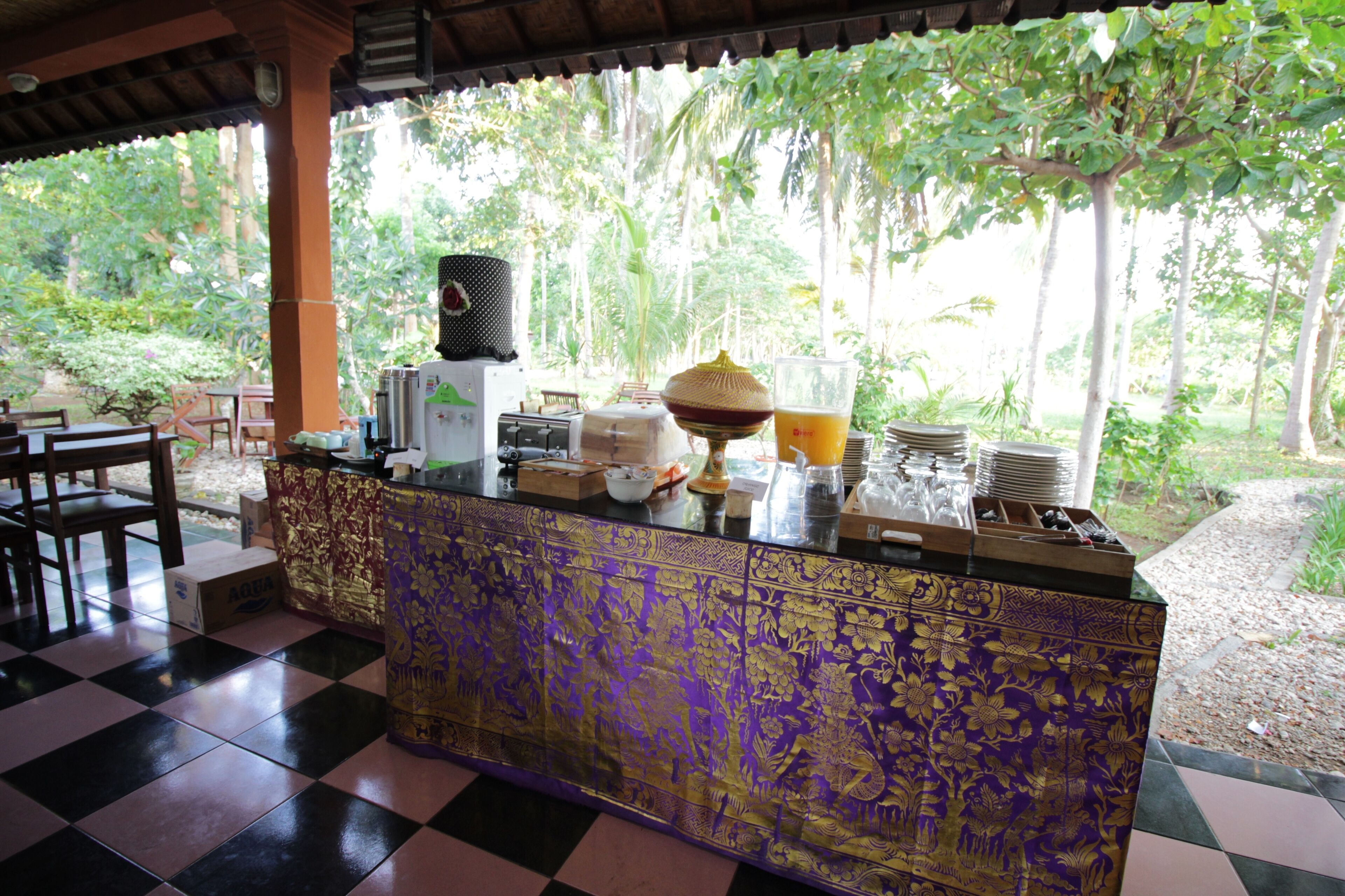 A checkered floor, a counter with a patterned design, and a view of greenery outside.