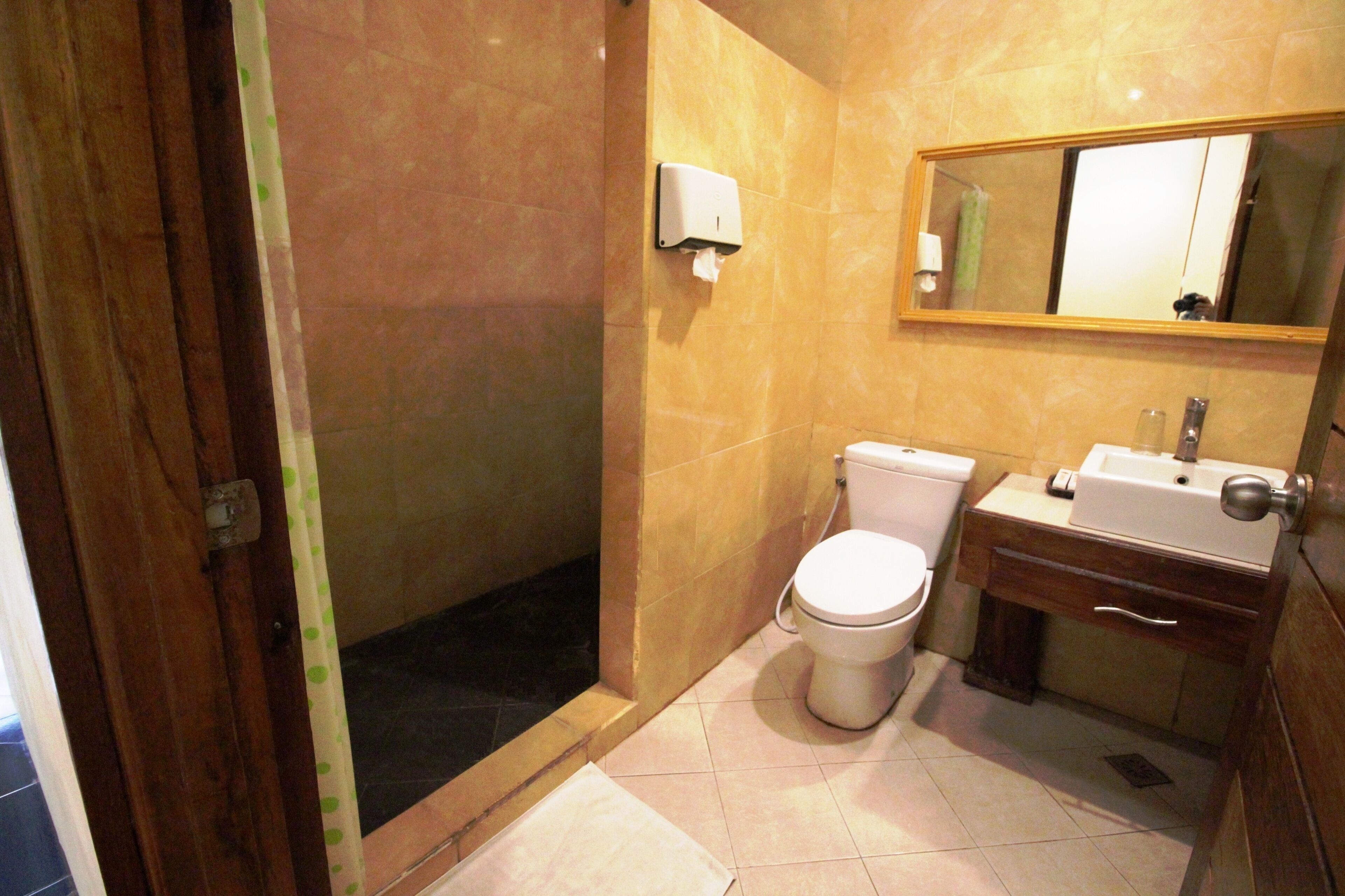 Un baño con inodoro, lavabo, espejo y dispensador de toallas de papel.