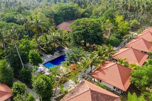 Un resort con varias edificaciones, una piscina y abundante vegetación.
