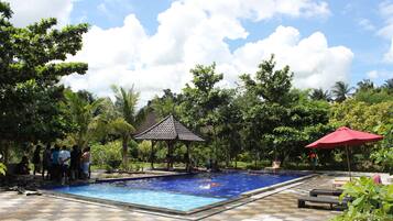 Relax by the serene pool surrounded by lush greenery and a shaded gazebo.