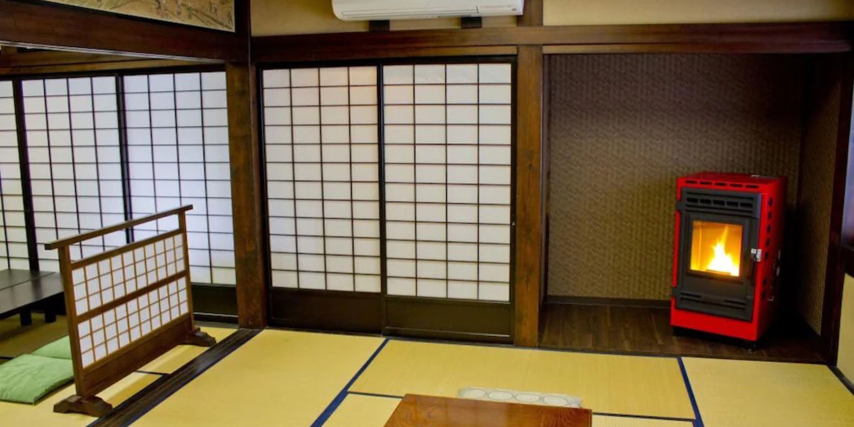 A traditional Japanese room with tatami flooring, shoji screens, and a wood-framed bed.