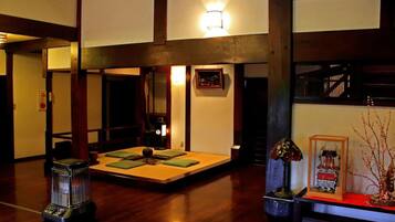A traditional Japanese-style room with tatami flooring, a low table with cushions, a heater, and a decorative lamp.