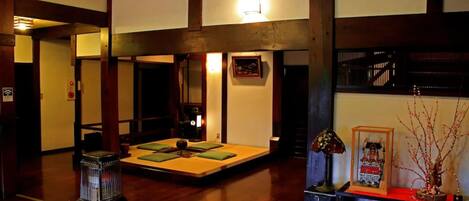 Una habitación de estilo japonés tradicional, con suelo de tatami, una mesa baja con cojines, un calentador y una lámpara decorativa.