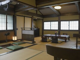 Una habitación tradicional japonesa con suelo de tatami, una mesa baja con cojines y un puertas correderas.