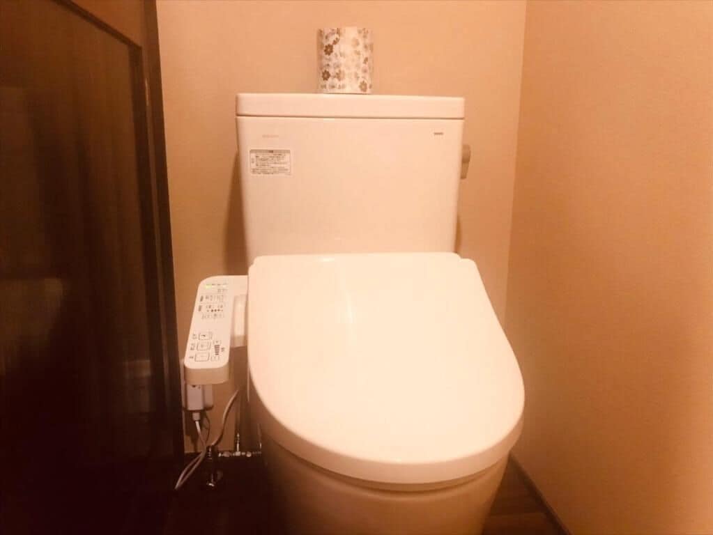 A white toilet with a control panel on the left.